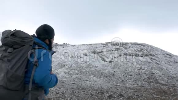 一个男性旅行者带着背包独自沿着一个高高的山脊行走视频的预览图