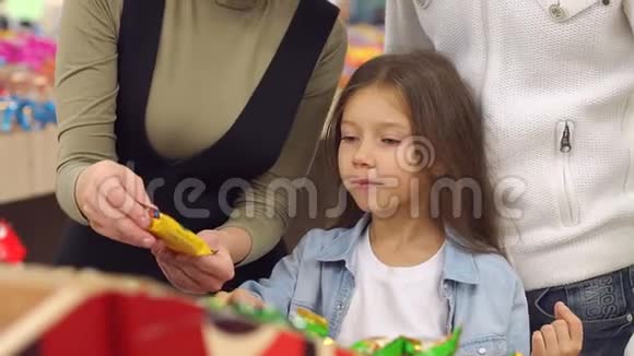 幸福的家庭和一个孩子在超市买糖果和糖果特写镜头视频的预览图