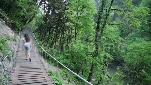 女孩走在山上森林的一座桥上视频的预览图
