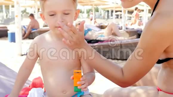 喜笑颜开的家庭在阳光明媚的天气在沙滩上涂抹紫外线防晒乳液4k视频视频的预览图