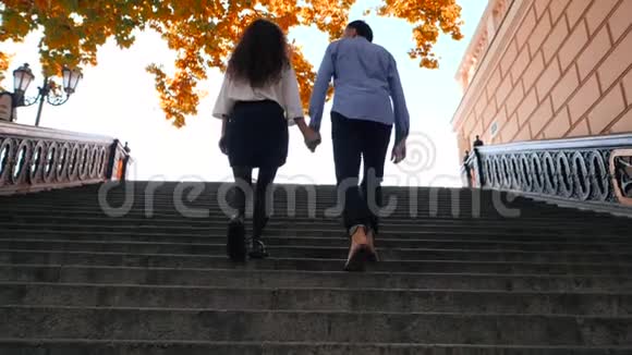 年轻时尚的一对男女走上楼梯学生的腿在秋天爬上旧的城市复古楼梯视频的预览图