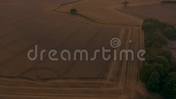 美丽的空中日落在乡村的英国乡村展现了史诗般的景观远景农民收割麦田视频的预览图