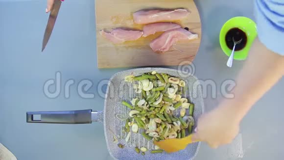 一个女人用木铲把豆子和洋葱和酱油混合在锅里视频的预览图
