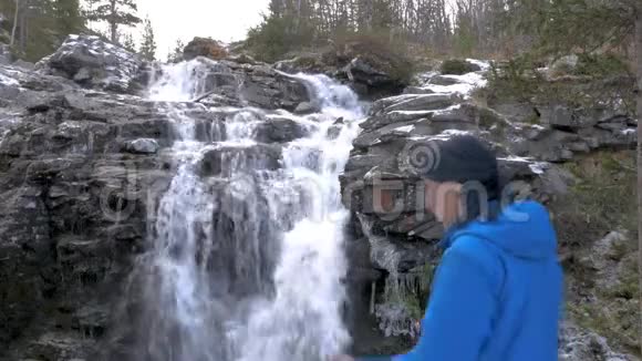 男性旅行者正在美丽的山瀑布下休息特写镜头他正在和他的朋友在收音机里交谈视频的预览图