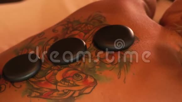 女人在水疗中心接受石头按摩特写热石用于女性身体背部按摩水疗治疗视频的预览图
