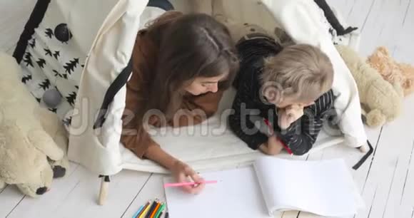 母亲和儿子一起在婴儿房的帐篷里画铅笔视频的预览图