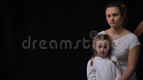 被殴打的母亲抱着她的女儿当骚扰的手触到她的肩膀时她感到害怕视频的预览图