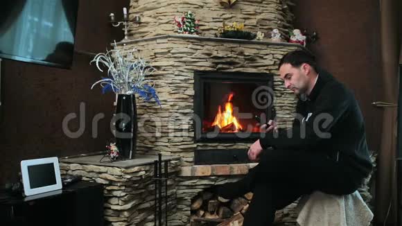 男人坐在壁炉旁边拿着一部智能手机视频的预览图