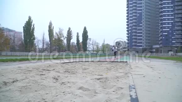 穿着运动服的帅哥加速跳在镜头前的沙子里沙子从脚下散落下来视频的预览图