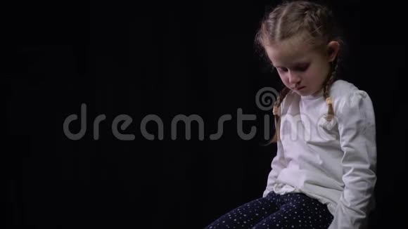 孤独而悲伤的小孩迷路了在黑色的背景下视频的预览图