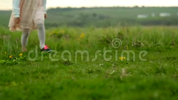 两个小女孩穿过绿色的草地孩子们脚视频的预览图