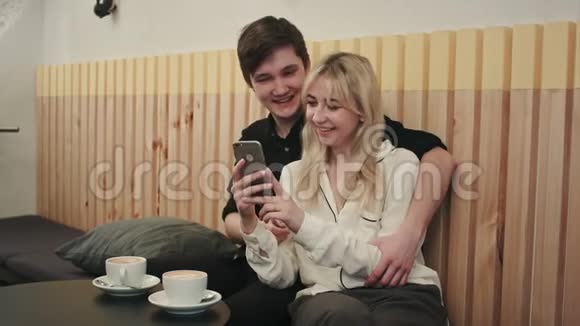 快乐的一对夫妇一起使用智能手机在咖啡馆里大笑视频的预览图
