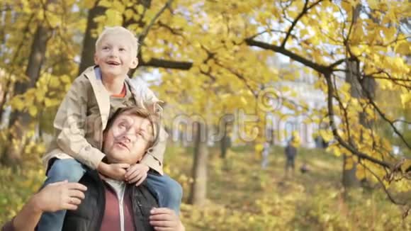 爸爸和一个小男孩在秋天的公园里散步视频的预览图