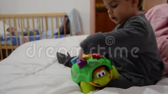 幼儿穿着睡衣玩乌龟教育玩具在婴儿床的不良与新生婴儿的早期发展视频的预览图