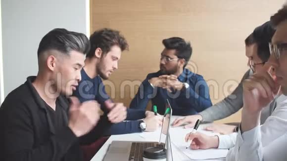 群聚的男性商务人士围着电脑在办公室聊天视频的预览图