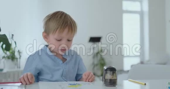 一个坐在桌子旁的小孩画了一幅不同颜色的铅笔画视频的预览图