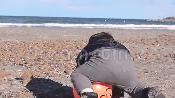 一个半岁的小男孩在沙滩上玩石头和球视频的预览图