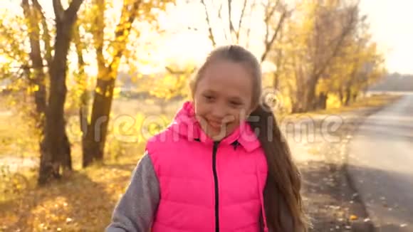美丽的少女骑着自行车在路上笑秋天一个留着长发穿着粉色夹克骑自行车的女孩视频的预览图
