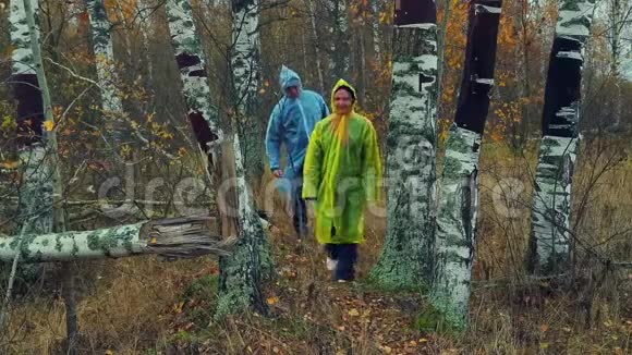 一男一女穿着雨衣在森林里散步视频的预览图