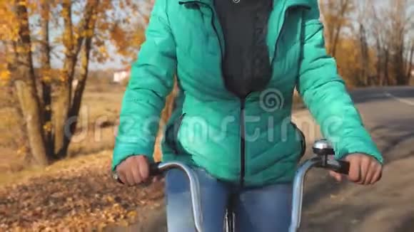 小女孩拿着弯曲的车把骑着自行车在秋天的公园里视频的预览图