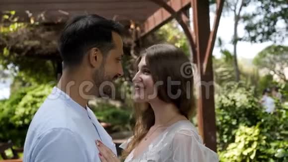新婚夫妇在花园的背景上相亲相爱行动美丽的年轻夫妇深情地看着每一个人视频的预览图