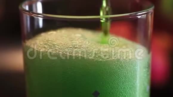 放大绿色雌龙饮料倒入水玻璃与大量气泡和泡沫视频的预览图
