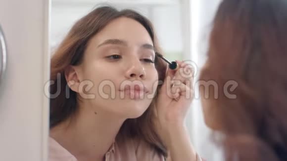 在浴室镜子上用刷子涂睫毛膏的漂亮女人视频的预览图