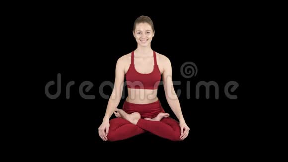 年轻的微笑女子练习瑜伽做帕德马萨纳运动莲花姿势阿尔法频道视频的预览图