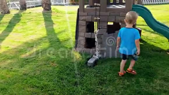 在阳光明媚的日子里小男孩在儿童操场上玩塑料玩具屋的4k视频视频的预览图