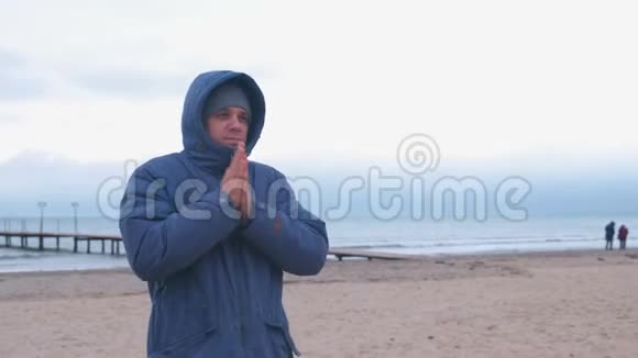 穿着海边夹克的人温暖冻僵的手等待着一个人视频的预览图