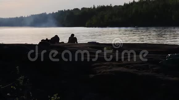 傍晚在湖上点燃火焰的人的两个轮廓视频的预览图