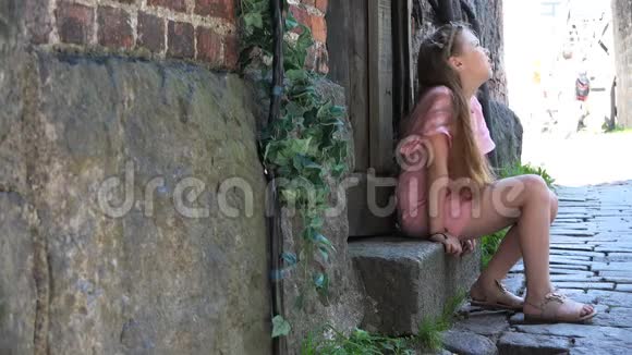一个疲惫的女孩坐在台阶上的木门旁视频的预览图