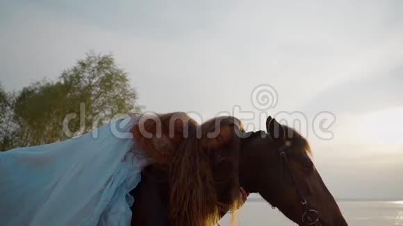 长头发的女孩穿着一件白色的连衣裙在马背上慢动作视频的预览图