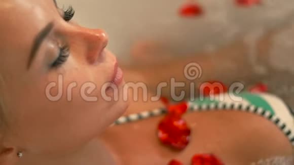 穿比基尼的肖像女人在水疗中心里用玫瑰花瓣按摩浴缸在豪华水疗中心享受按摩浴缸的面部女士视频的预览图
