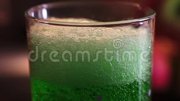 近距离观察泡沫如何消失在绿色埃斯特龙柠檬水在水玻璃视频的预览图