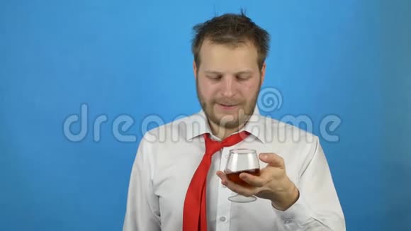 一个留着胡子的年轻人穿着一件白色衬衫打着领带拿着一杯酒想喝酒但却停了下来视频的预览图
