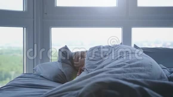 英俊的男人睡在窗边的床上慢动作视频的预览图
