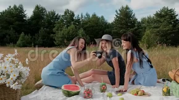 三个年轻漂亮的女孩在野餐摄影师在两个模特的无镜相机上拍照模型视频的预览图