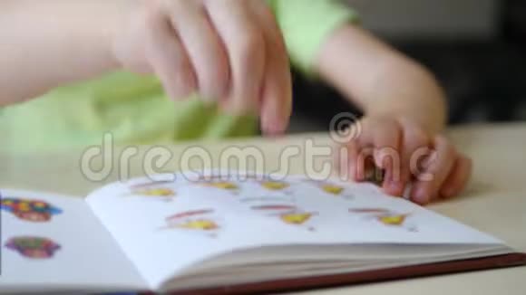 一个手指的孩子在家里指着书中的图画坐在一张灯点亮的桌子旁视频的预览图