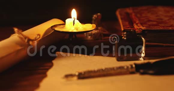 老式琴笔和墨水瓶放在烛光下的旧羊皮纸上视频的预览图