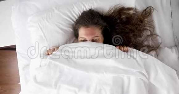 开朗的女人躲在毯子床后面视频的预览图