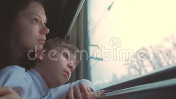 疲惫的母亲和儿子正在冬天的风景上看着火车的窗户视频的预览图