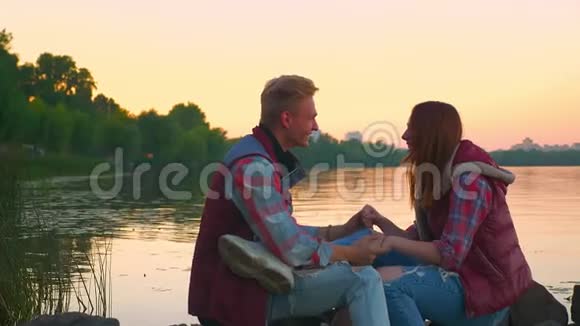 恋爱中的年轻人坐在河底的石头上男人亲吻女孩的额头视频的预览图