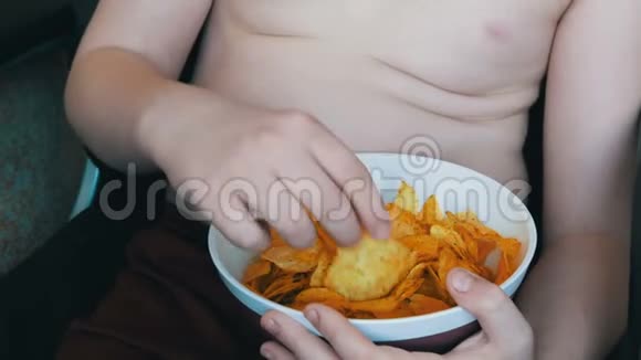肥胖的少年身体上有脂肪褶皱正在吃薯片不健康食品快餐儿童营养问题视频的预览图