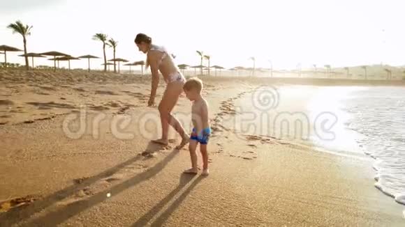 日落时分小男孩和妈妈在沙滩上散步视频的预览图