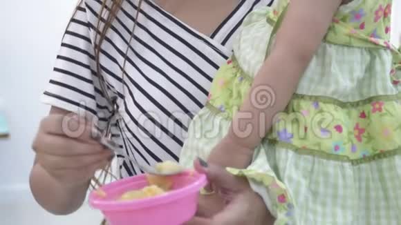 亚洲母亲在家为女儿喂饭面带微笑幸福的亚洲家庭理念视频的预览图
