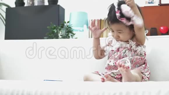 快乐的亚洲女孩独自在家沙发上玩耍4K美丽的女孩子的慢动作视频的预览图