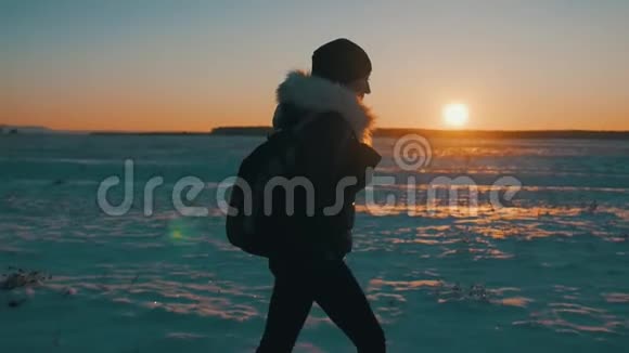 一个年轻快乐的女孩旅行者的剪影带着背包在日落时去冬季旅行生活方式自由的概念视频的预览图