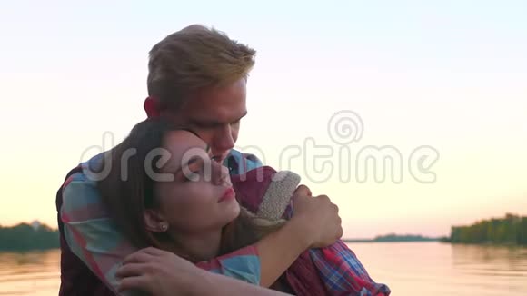 一个男的正在抱着他的女人特写镜头而她正在放松闭着眼睛看着水的背景幸福视频的预览图