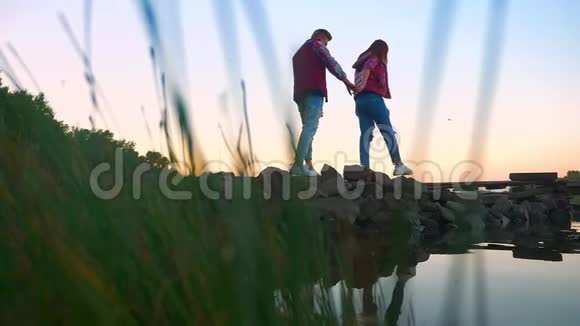 视频中女性和她的男朋友走着尖石走着互相牵着手自然水和视频的预览图
